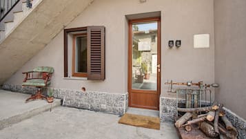 L’entrée d’un bâtiment avec une porte en bois, une fenêtre avec des volets, une chaise et une pile de bûches.