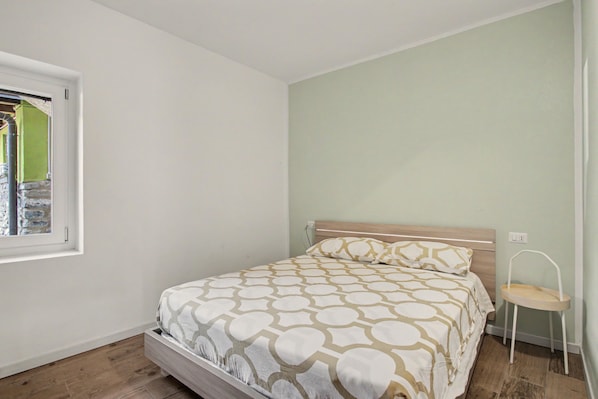 Una camera da letto con un letto, una finestra, una sedia e una presa elettrica.
