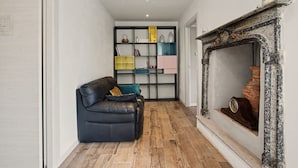 Una sala de estar con un sofá de cuero negro, una chimenea y una estantería con varios objetos.
