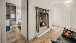 Una sala de estar moderna con chimenea, piso de madera y un sofá con un cojín decorativo.