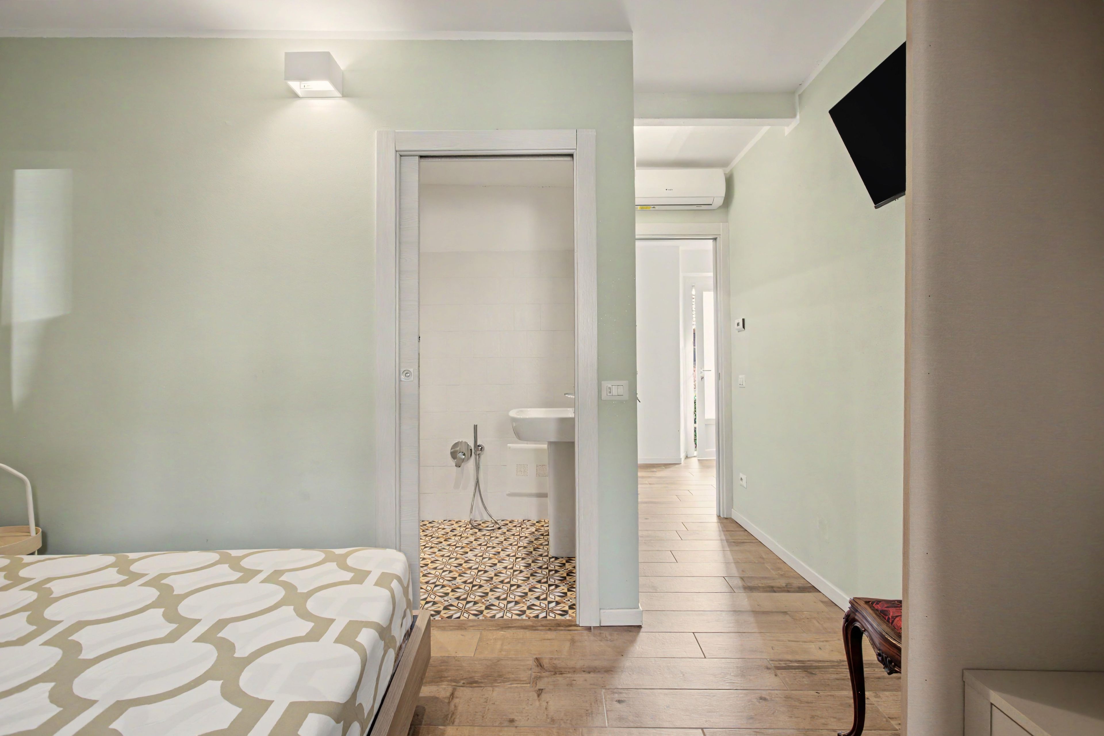 Een hotelkamer met een bed, een douche en een gang naar de badkamer.
