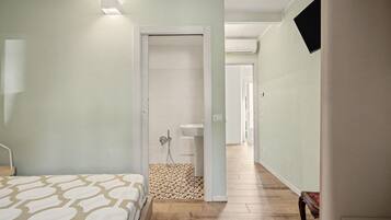 Een hotelkamer met een bed, een douche en een gang naar de badkamer.