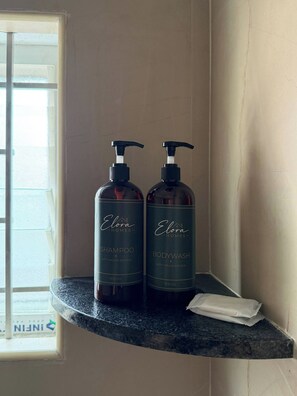 Two bottles of Elora Homes shampoo and body wash on a dark countertop. - The golden hour by Elora Homes: 2BHK in Arekere (Bengaluru)