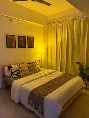 A bedroom with a bed, a floor lamp, and a potted plant. - The golden hour by Elora Homes: 2BHK in Arekere (Bengaluru)