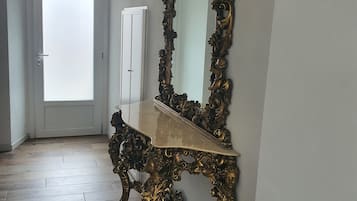 A room with a large ornate mirror, a wooden floor, and a white door.