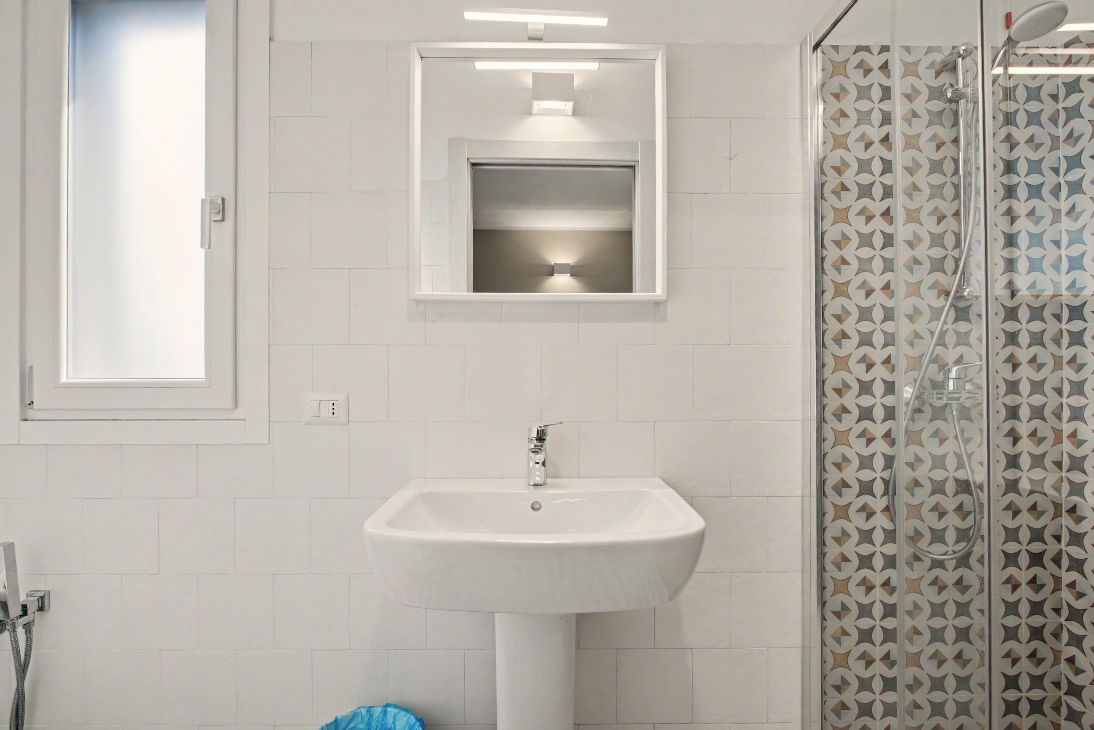 Een badkamer met een wit wastafel, een spiegel en een douchecabine.