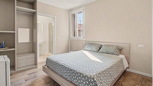 Un dormitorio con cama, armario y ventana.