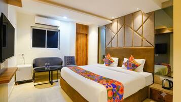 A hotel room with a bed, bedside table, chair, and a small desk with a chair.