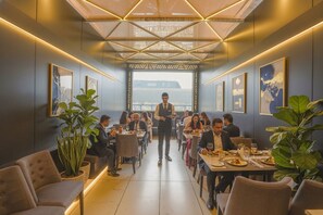 A modern dining area with tables, chairs, and a waiter. - Hotel Casa Annex (Mumbai)