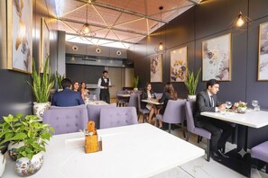 A restaurant with purple upholstered booths, a white central table, and framed artwork on the walls.