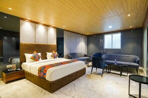 Une chambre d’hôtel moderne avec un grand lit, un coin salon et une fenêtre.