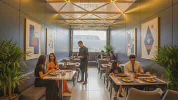 A modern dining area with tables, chairs, and waitstaff.