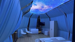 A tent-like room with a bed, a small table, and a chair.