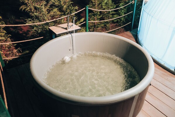 Un jacuzzi con grifo, rodeado por una barrera de cuerda y follaje.