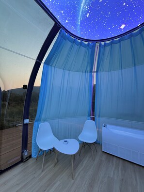 Ein Zimmer mit Sternenhimmel-Decke, zwei weißen Stühlen und einer weißen Klimaanlage.