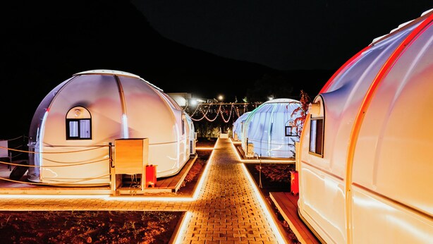 A row of dome-shaped structures with a paved walkway leading to them, each with a small window and a door.