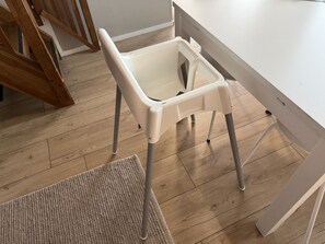 A white chair with a storage compartment, a wooden floor, and a white table.