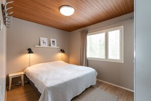 A bedroom with a bed, two wall-mounted lamps, a window with curtains, and a ceiling light.