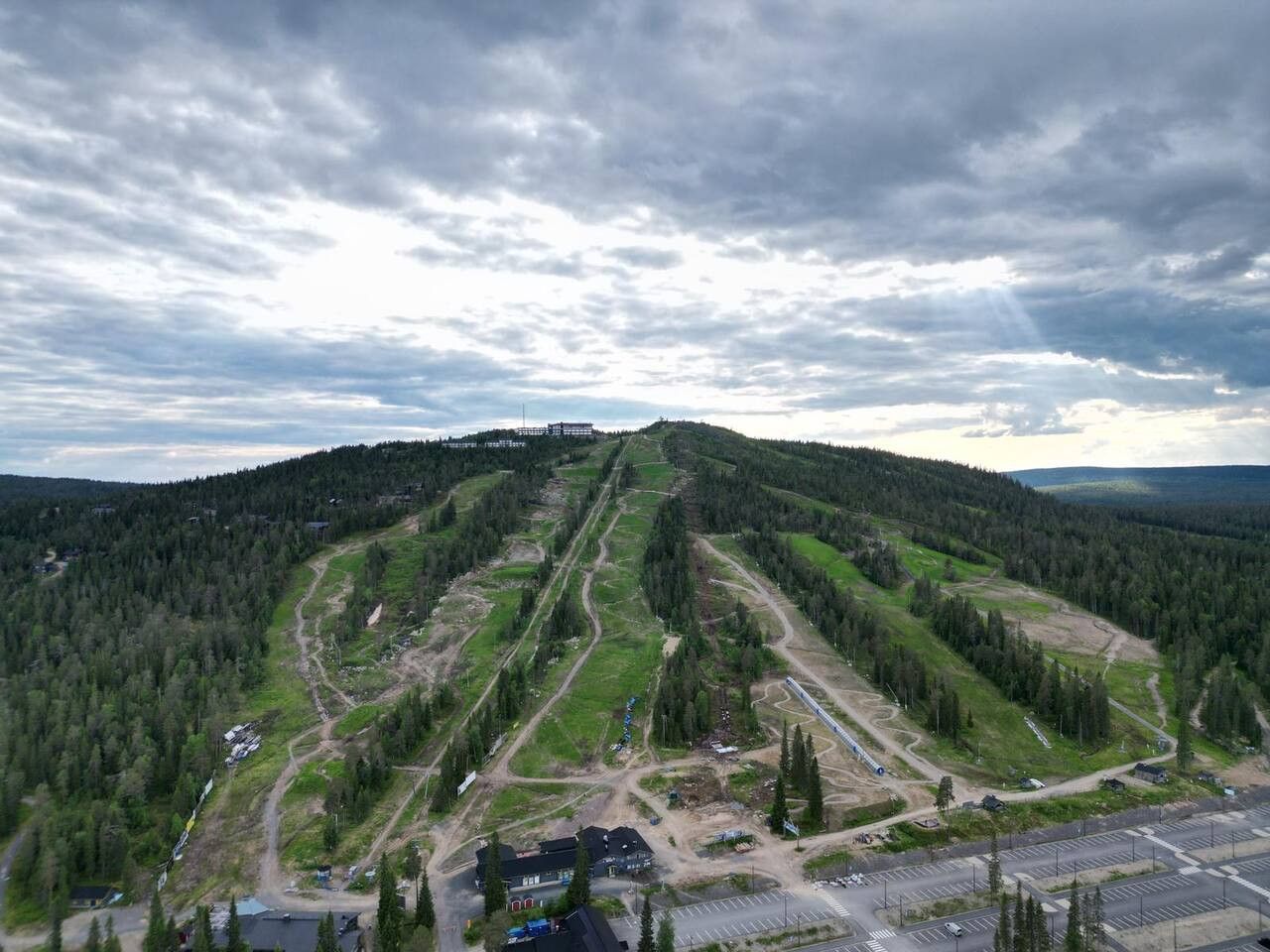 An aerial view of a mountainous area with a ski resort, including ski trails and lodges.