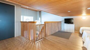 Een kamer met een houten plafond, een televisie, een bed en een witte dressoir.