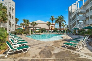 A hotel pool area with sun loungers and a central pool. - Cute condo on Seawall across from beach (Galveston)