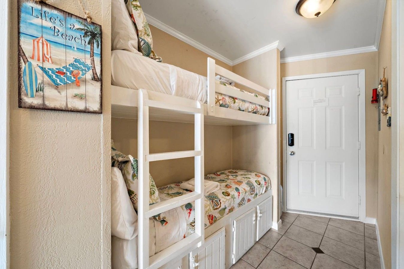 A room with bunk beds, a door, and a wall decoration.