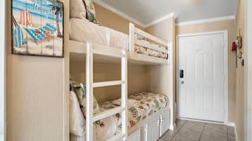 A room with bunk beds, a door, and a wall decoration.
