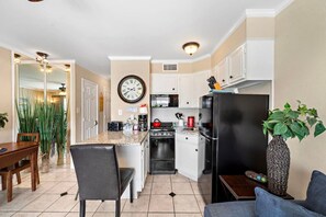 Una cocina compacta con comedor, un reloj en la pared y una planta en la encimera.