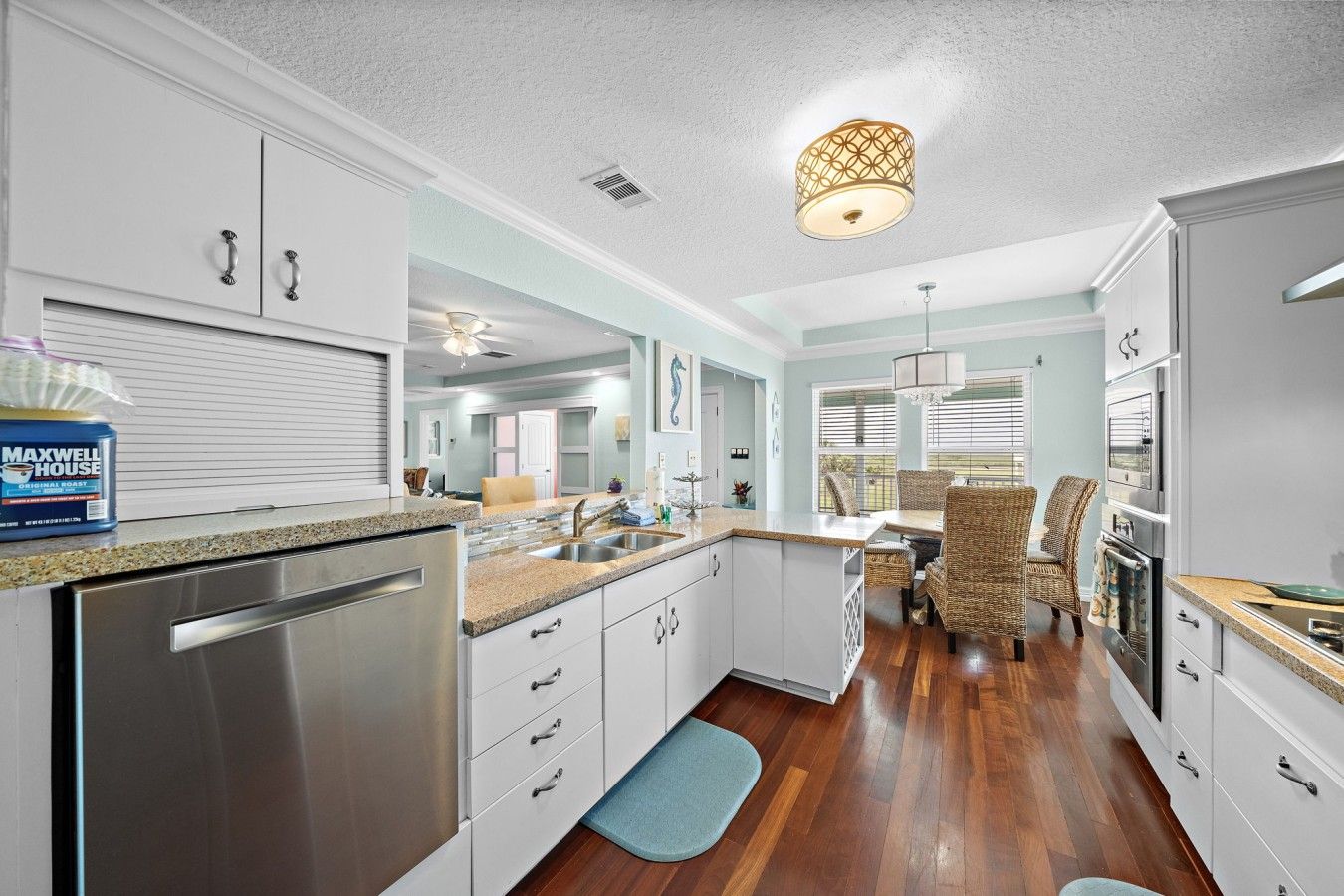 A modern kitchen with granite countertops, stainless steel appliances, and a dining area with wicker chairs.