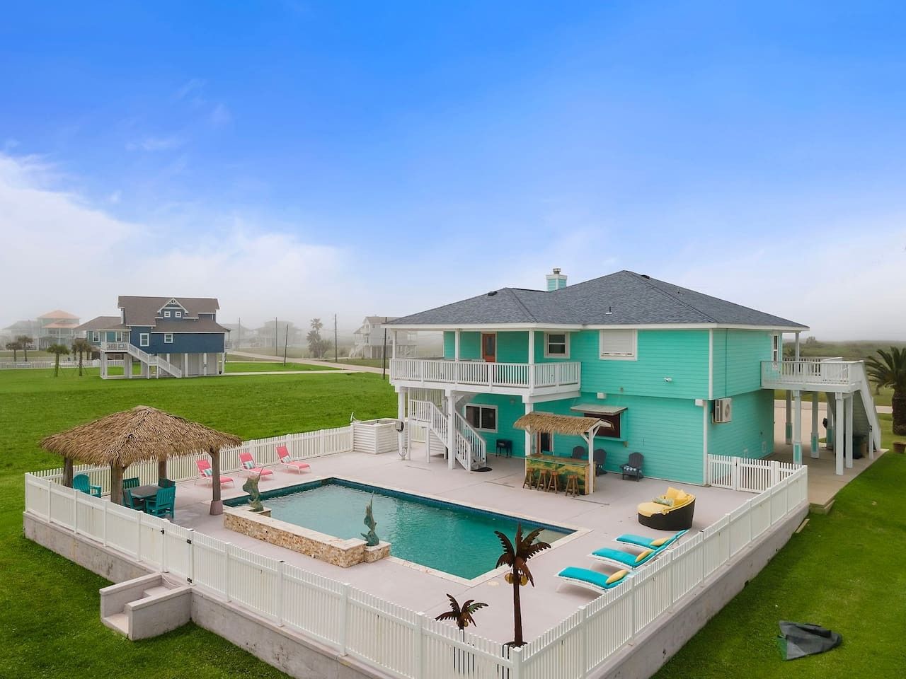 Une maison à deux étages avec une piscine, un patio couvert et une clôture blanche.