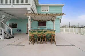 A beach house with a bar area featuring a thatched roof and wooden stools. - Ranger Resort- Pool/Patio- Close to Beach (Galveston)