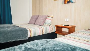 Une chambre avec deux lits, une table de chevet et un interrupteur fixé au mur.