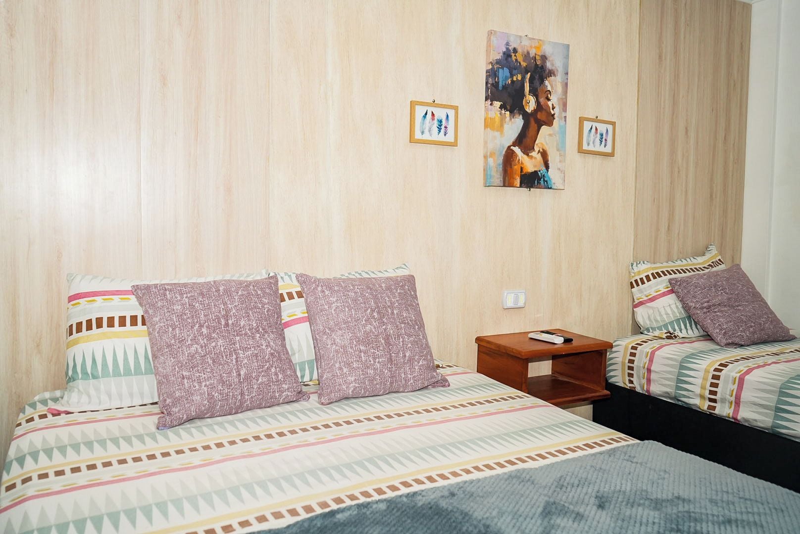 Quarto de hotel com duas camas, uma mesa de cabeceira e um quadro na parede.