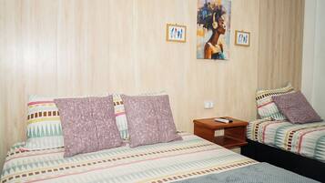 Quarto de hotel com duas camas, uma mesa de cabeceira e um quadro na parede.