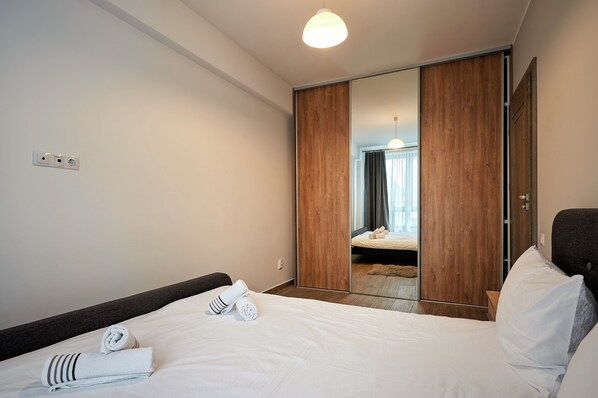 Een hotelkamer met een bed, een kledingkast en een spiegel die een badkamer weerkaatst.