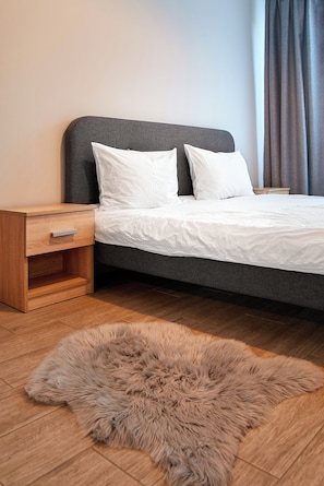 A modern bedroom with a bed, wooden nightstand, and a fur rug on the floor. - NUUC Aparthotel (Cluj-Napoca)