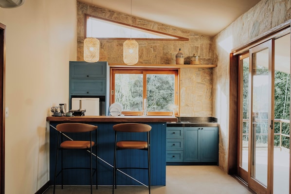 A kitchen with a bar area, wooden beams, stone walls, and a large window. - Villa Arouca (Areal)