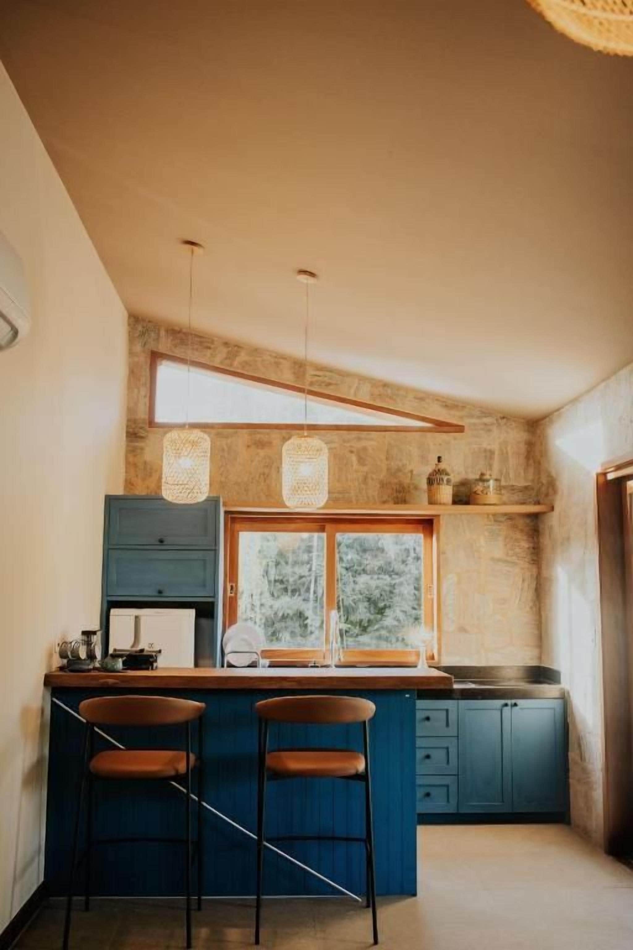 Une cuisine dotée d’un îlot central, de tabourets de bar, d’une fenêtre et de luminaires suspendus.