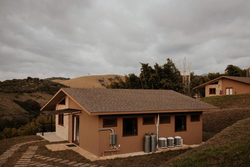 A single-story building with a sloped roof, a small porch, and two visible windows. There are three cylindrical tanks outside the building.