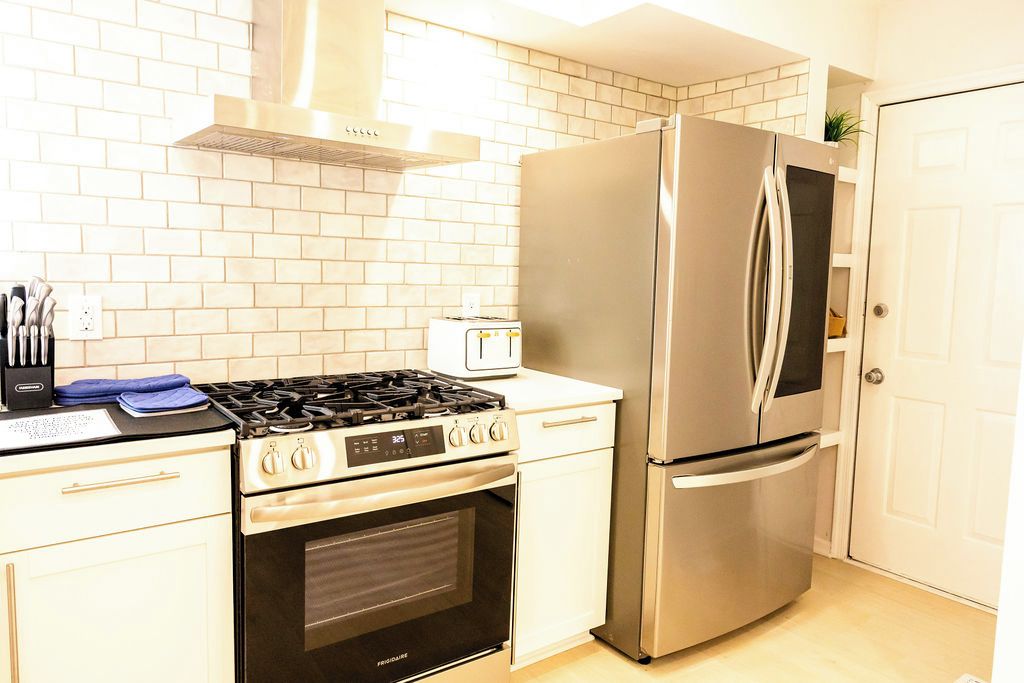 A kitchen with a stainless steel refrigerator, a gas stove, and a built-in oven.
