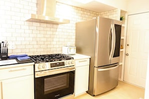 Une cuisine équipée d’un réfrigérateur en acier inoxydable, d’une cuisinière à gaz et d’un four encastré.