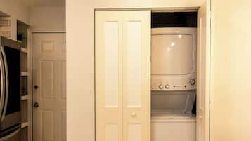 A laundry room with a washing machine and dryer, a door, and a microwave.