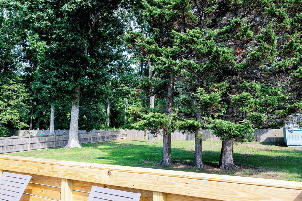 A wooden deck with a view of a grassy yard and trees.