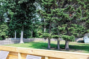 Une terrasse en bois offrant une vue sur une pelouse et des arbres.