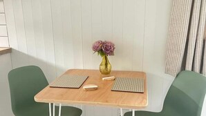 Ein kleiner Essbereich mit einem Holztisch, zwei grünen Stühlen, einer Blumenvase und einer Tastatur auf dem Tisch.