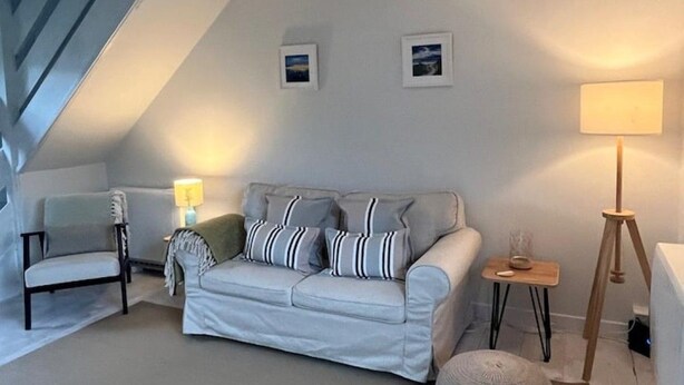 Ein gemütliches Wohnzimmer mit einer Couch, zwei Sesseln, einer Lampe und einem kleinen Tisch.