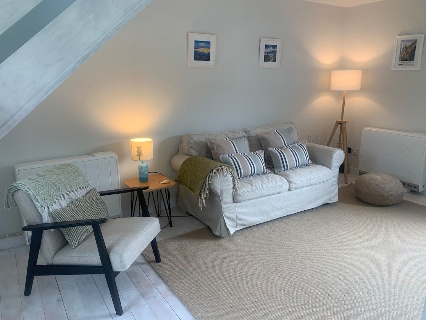 Een gezellige woonkamer met een bank, een fauteuil, een lamp en een radiator.