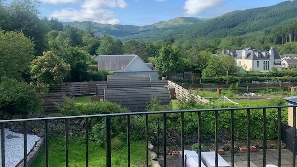 A residential area with houses, a fenced garden, and a mountainous backdrop.