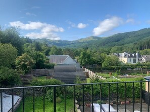 A residential area with houses, a fenced garden, and a mountainous backdrop. - Airlie Cottage (Callander)