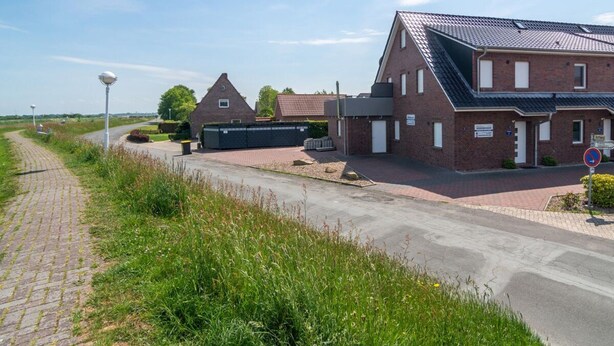 A brick building with a sloped roof, a paved driveway, and a no parking sign. - Holiday Home With 1 Bedroom (Esens)